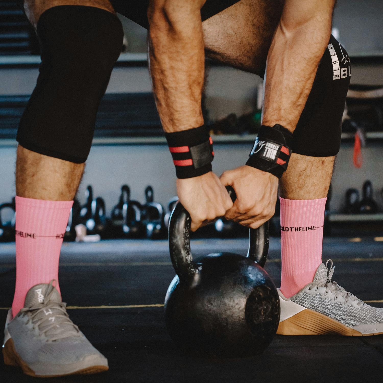 A person preparing to lift a kettlebell in a gym